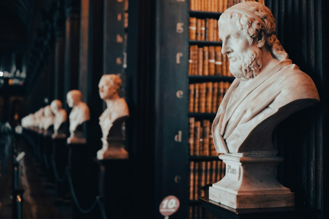 Historic library room filled with books and statues